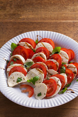 Italian caprese salad with sliced tomatoes, mozzarella cheese, basil, olive oil and balsamic vinegar