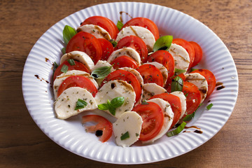 Italian caprese salad with sliced tomatoes, mozzarella cheese, basil, olive oil and balsamic vinegar