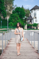 Young woman walks along waterfront. Brunette woman in gray summer dress