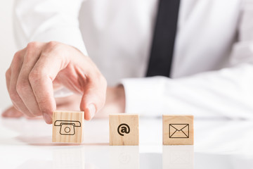 Businessman placing cubes with email and phone pictograms