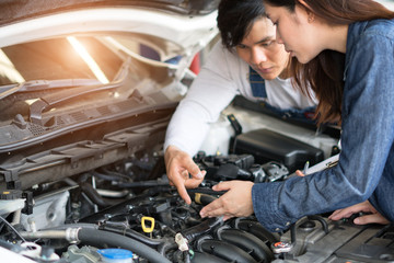 A man mechanic and woman customer look at the car hood and discuss repairs.
