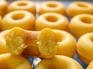 Close-up image of one half on top of group of baked butter milk donuts