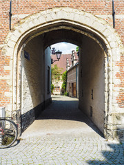 Fototapeta na wymiar Small entrance gate to a cobblestone alley in the large beguinage in Mechelen, Belgium