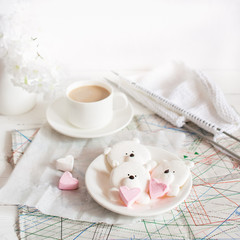 A delicious marshmallow dessert in the form of bears and a mug with a drink on the desktop.