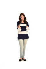 full length portrait of girl wearing striped blue and white jumper and jeans. standing pose on white studio background
