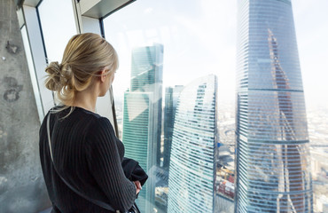 Woman looking at the skyscrapers. Watching cityscape from skyscraper interior