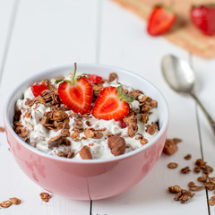 Granola with yogurt, strawberry in a pink bowl, healthy breakfast