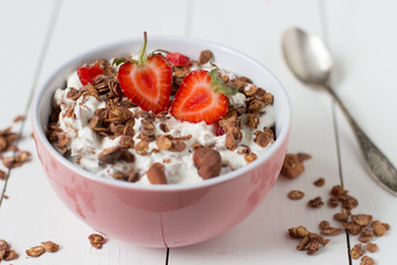 Granola with yogurt, strawberry in a pink bowl, healthy breakfast