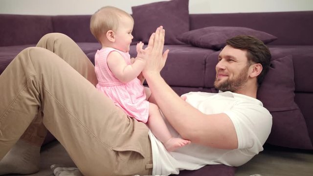 Dad with baby playing hands. Happy father give five to daugther. Daddy enjoy time with kid. Joyful man playing with child girl. Smiling father and toddler girl play with hands. Time for game