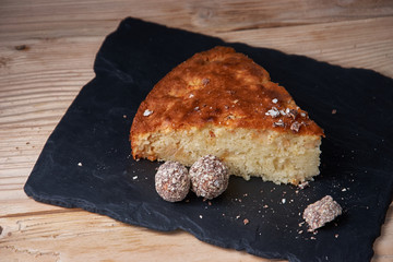 A piece of apple pie with grated chocolate near chocolate truffle candies. Selective focus and small depth of field.