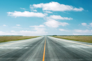 Asphalt road through the green field and clouds on blue sky in summer day.