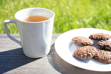 A cup of tea and the biscuits on the wooden table in the early morning. Light breakfast