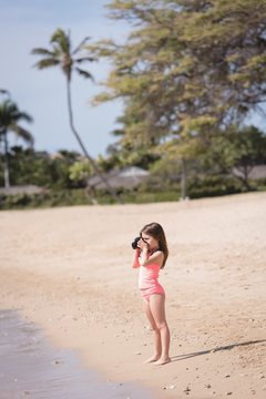 Girl clicking photo of sea with camera