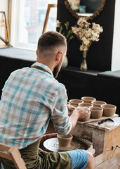 Man is  shaping bowl on potters wheel