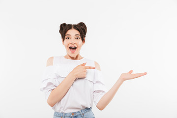 Photo of advertising teenage woman with double buns hairstyle and dental braces pointing finger at copyspace holding on palm, isolated over white background
