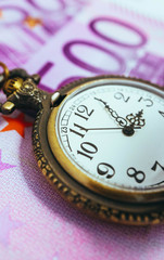 Old pocket watch with euro banknotes money, macro view. Time and business concept.