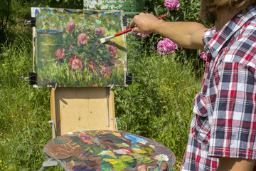 male artist paint on plein air flowers pink peonies painting in garden landscape on nature