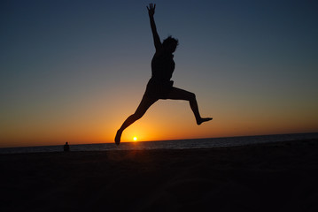 CHICA SALTANDO EN LA PLAYA AL ATARDECER