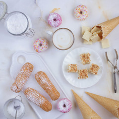 Eclairs and donuts with coffee on a marble background, Light background, Confectionery in a blogger style