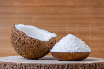 coconut flakes in a bowl on brown wooden background