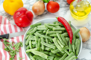 Green beans in the white plate on  grey and white background.
