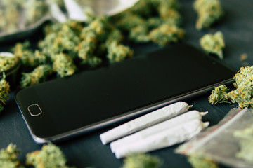 weed Joint Macro of cannabis buds marijuana. Black Smartphone, with trichomes and crushed weed on a...