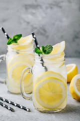 Homemade refreshing summer lemonade drink with lemon slices and ice in mason jars