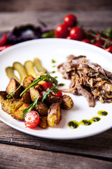 Meat in a sauce of white mushrooms and fried potatoes. Food