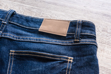 Blue jeans on wood background with leather label.
