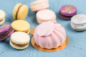 Pink mousse-cake. French macaroon dessert and flowers eucalyptus on a turquoise background. pastel colors
