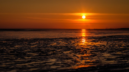 The sky gets darker and turns orange as the sun has almost set on the shores of the Wadden Island of Schiermonnikoog (Friesland, the Netherlands) on a September evening.