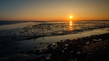 The sky gets darker and turns orange as the sun has almost set on the shores of the Wadden Island of Schiermonnikoog (Friesland, the Netherlands) on a September evening.