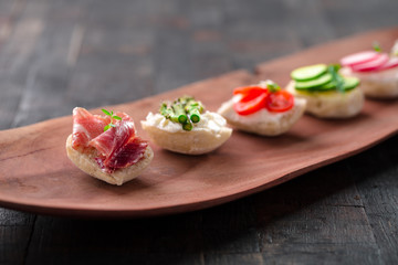 Set of different mini sandwiches on a wooden board.