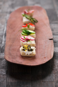 Set of different mini sandwiches on a wooden board.