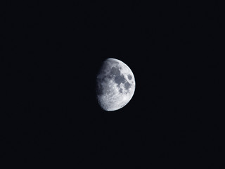 Natural night background with dark sky and half Moon, Earth satellite. Waxing gibbous phase.