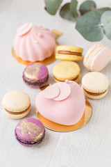 Pink mousse-cake. French macaroon dessert and flowers eucalyptus on a white background. pastel colors