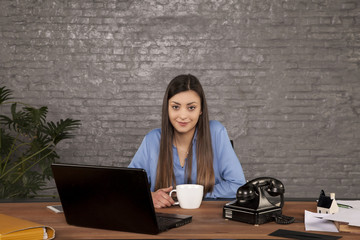 portrait of a business woman sitting behind a desk and drinking coffee