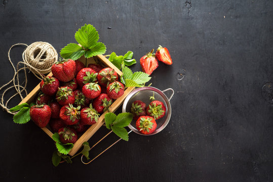 Fresh tasty strawberries in wooden box on black background.