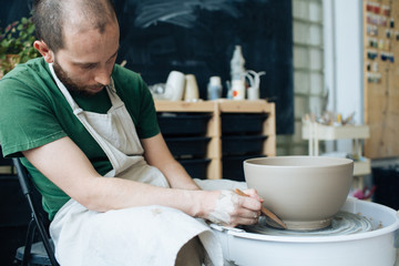 Handcrafted on a potter's wheel,Hands make clay from various items for home and sale in the store and at the exhibition, ceramic items are made in hand, stylish bearded young man makes products 