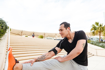 Handsome young sportsman doing stretching exercises outdoors.