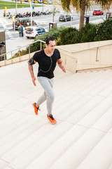 Sportsman running on steps outdoors in earphones.