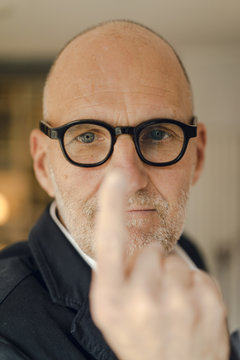Senior man with glasses, focusing on his index finger
