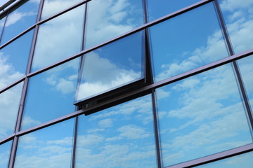 The blue sky is reflected in the glass building. Window's open.