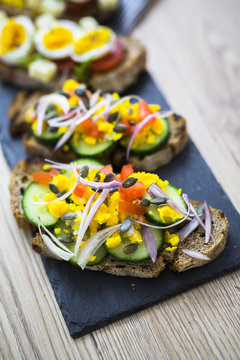 Vegetarian breakfast with bread, eggs and cucumber slices on slate