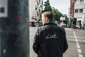 Back view of young man wearing black leather jacket with writing 'Love'