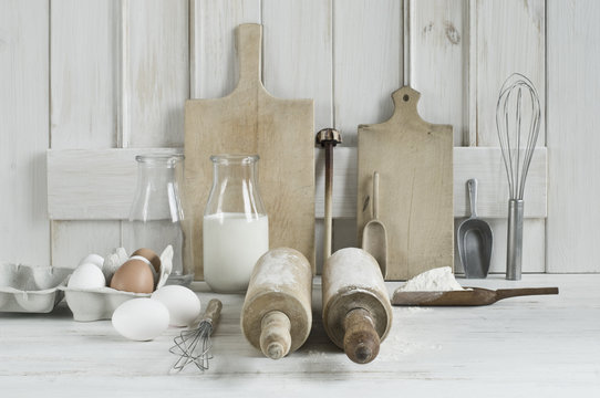Kitchen utensils, rolling pin, wire whisk, shovel, chopping board, eggs, flour and milk