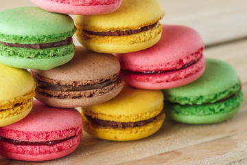 Green, pink, yellow and brown french macarons on the wooden boards