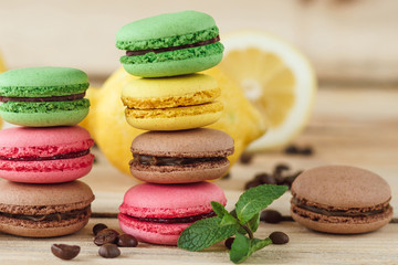 Green, pink, yellow and brown french macarons with lemon and coffee beans