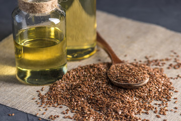 Flax seeds with spoon and linseed golden oil in a glass bottle on the table. Healthy diet with omega 3 fatty acids.