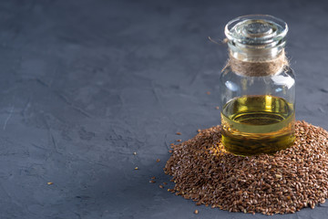 Flax seeds in a pile and linseed golden oil in a glass bottle on a dark background. Diet with omega 3 fatty acids.